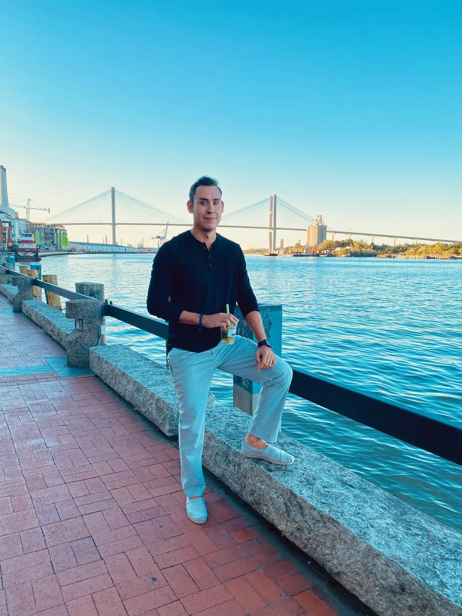 A man sitting on a railing near the water.